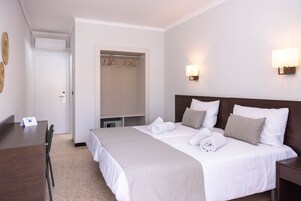 A hotel room with a bed, bedside tables, a desk, and a chair.