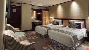 Habitación de hotel con dos camas, un escritorio, una silla y un televisor.
