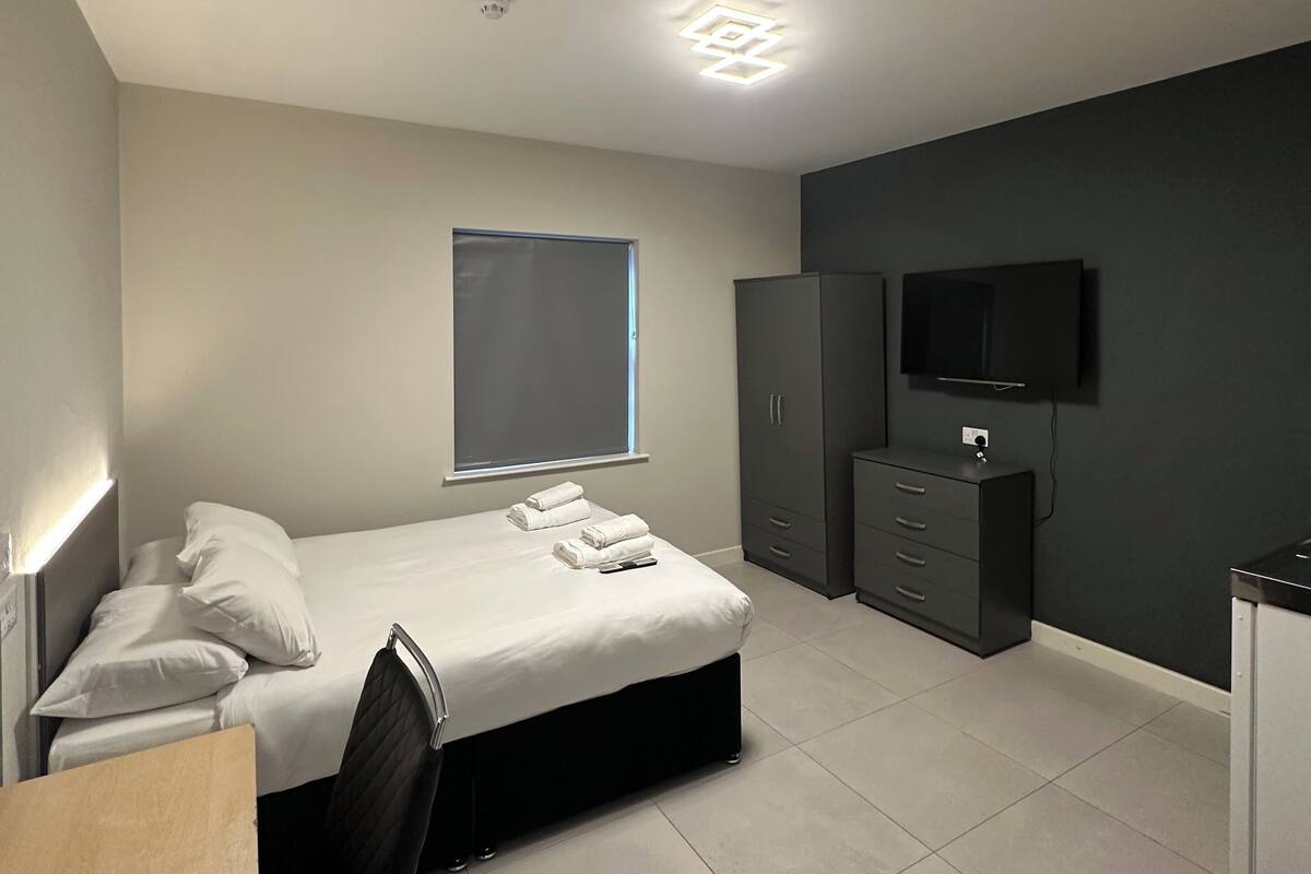A modern bedroom with a bed, wardrobe, and TV.