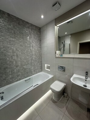 Een moderne badkamer met een bad, toilet en wastafel.