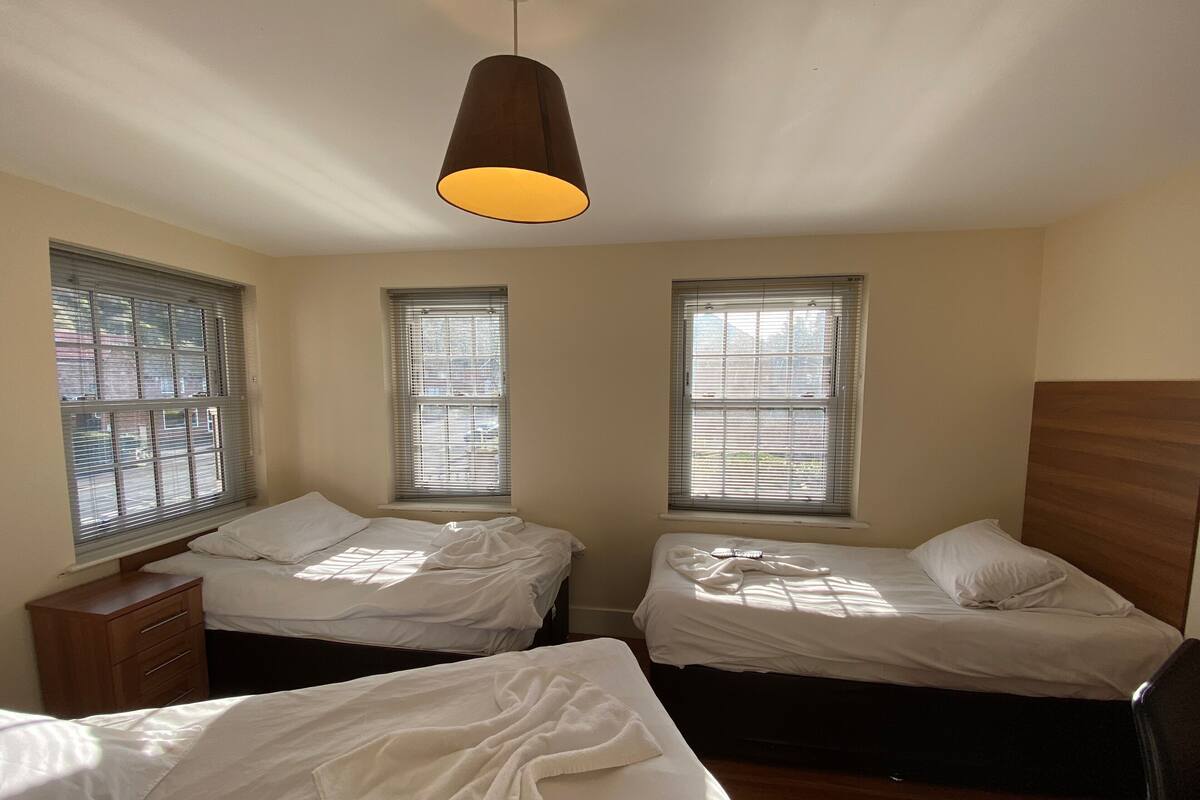 A room with two single beds, a wooden dresser, and a hanging light fixture.