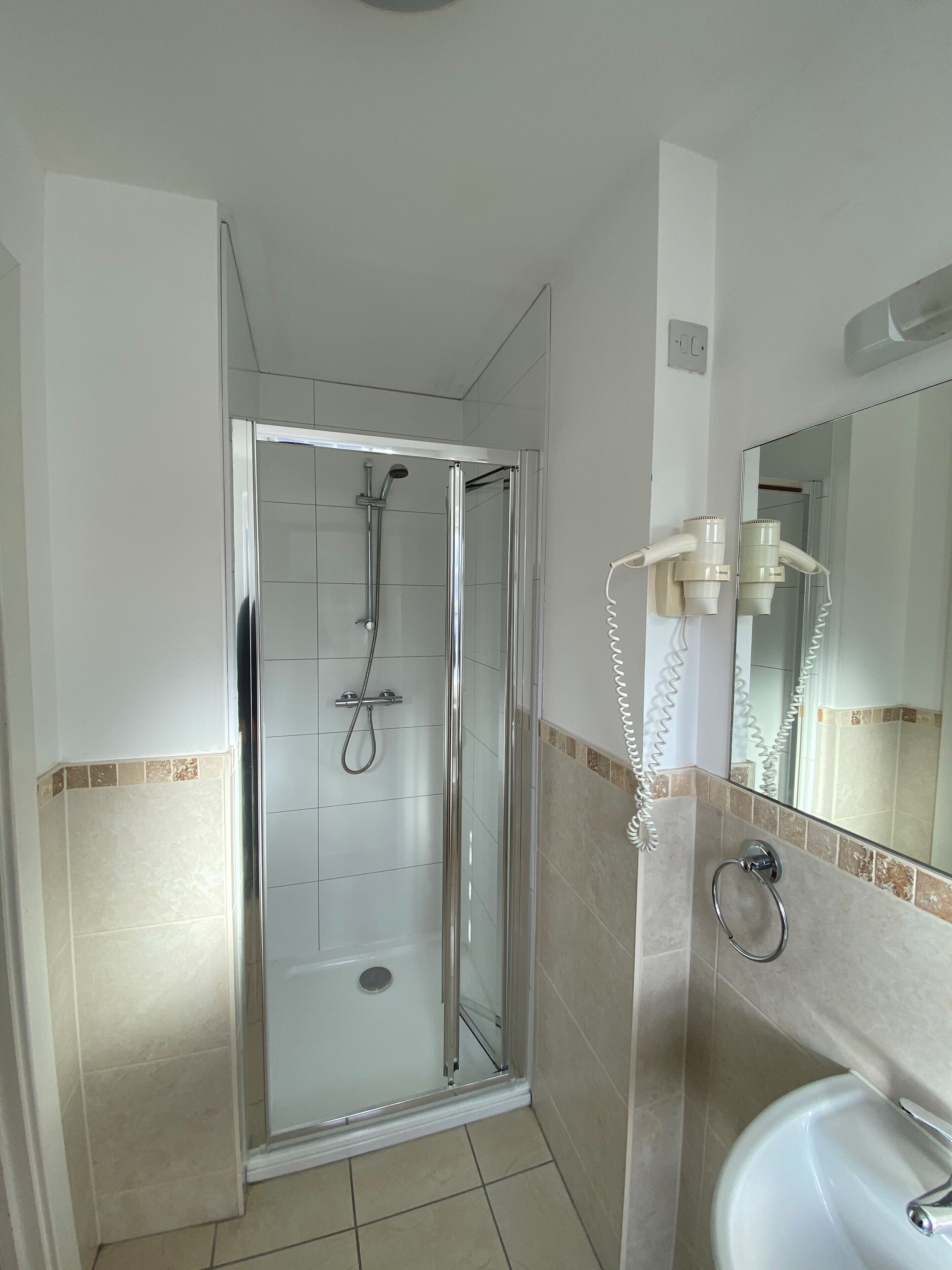 A bathroom with a glass-enclosed shower, a sink with a mirror, and a towel rack.