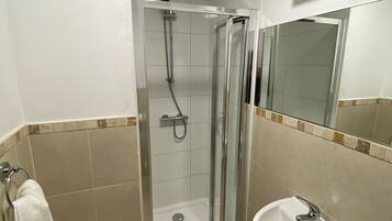 A modern bathroom with a glass-enclosed shower, a white sink, and a toilet.