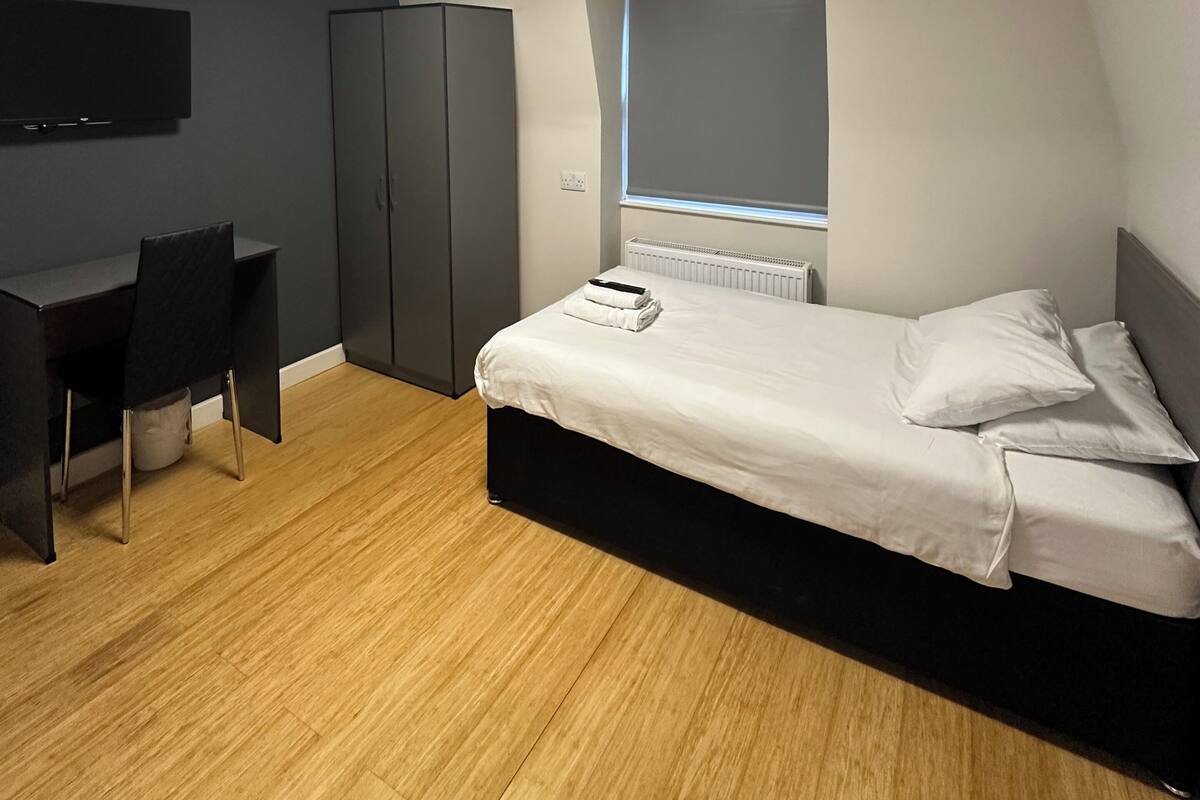 A modern bedroom with a bed, a desk, and a wardrobe.