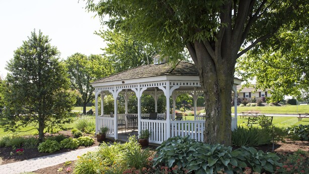 A gazebo with a white railing, surrounded by a garden with various plants and flowers. - Travelers Rest Motel (Gordonville)
