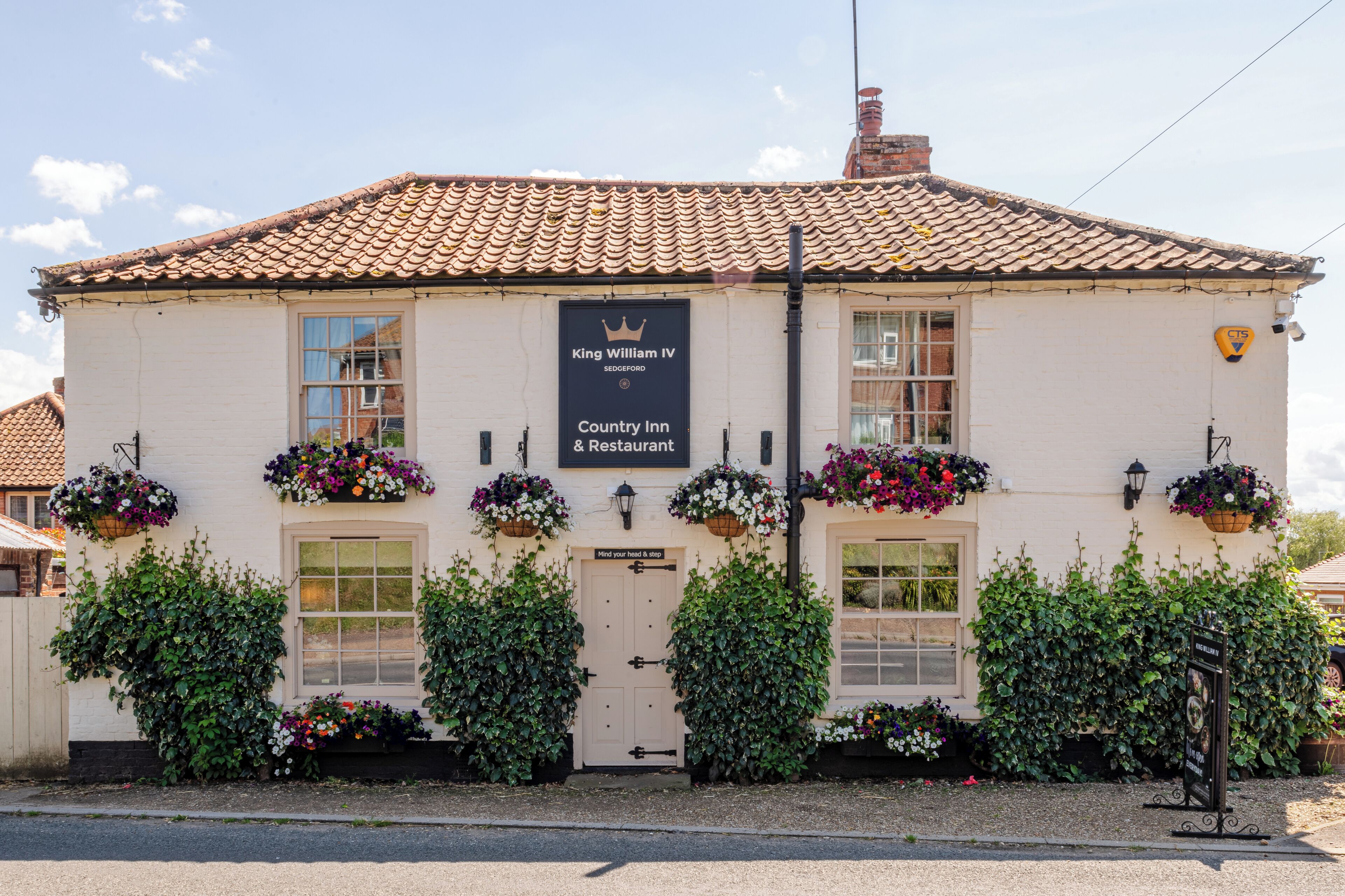 A building with a sign reading "King William IV Country Inn & Restaurant" and a crown emblem.