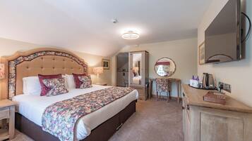 A bedroom with a large bed, a bedside table, a mirror, a dresser, and a ceiling light.