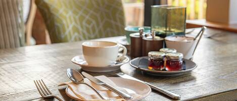 A dining table set with a cup, saucer, plate, cutlery, and condiments.