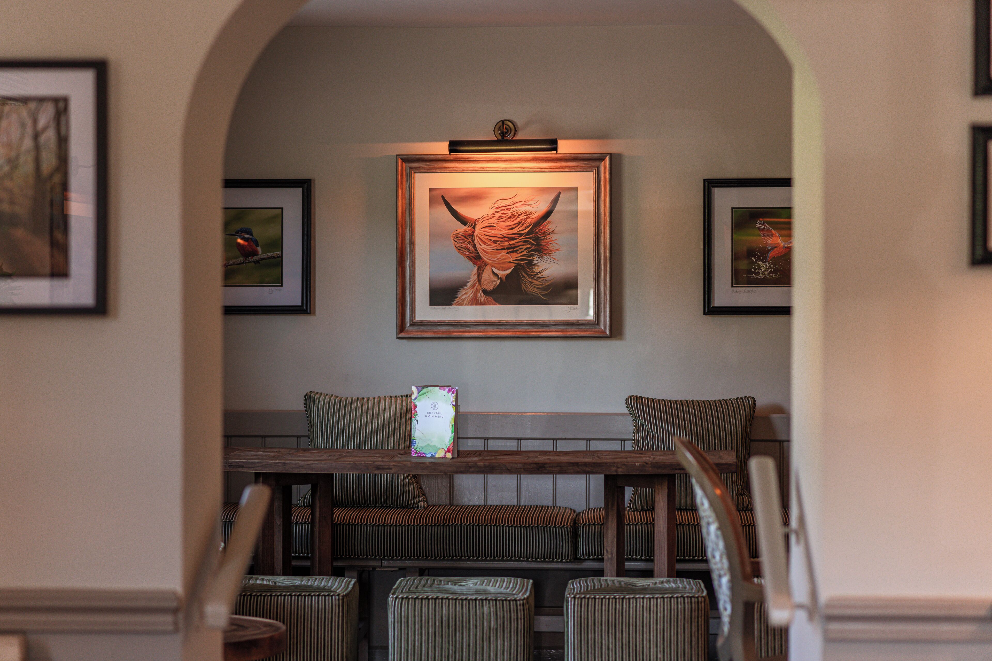 A reception area with a wooden bench, framed artwork, and a staircase leading to upper levels.