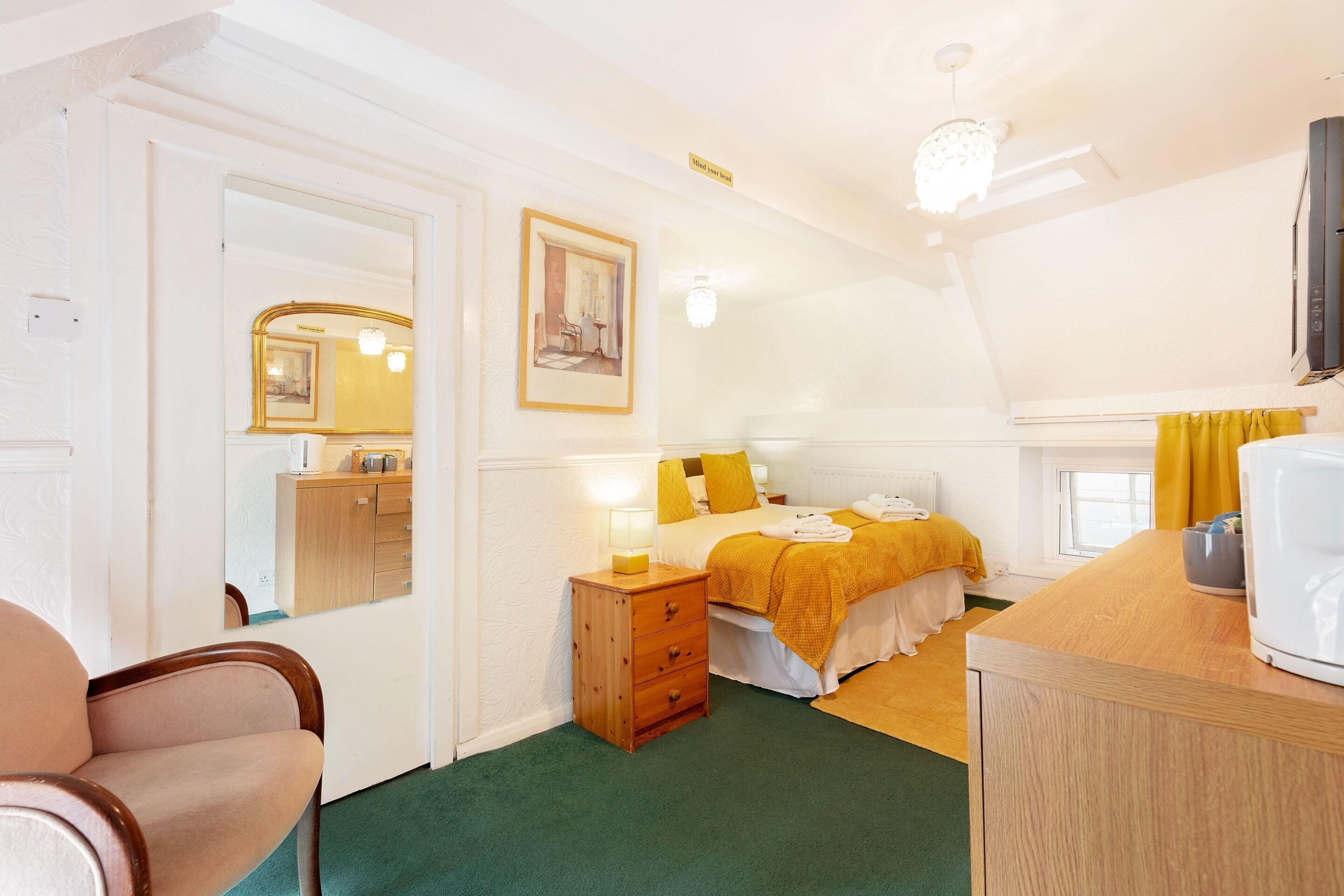 A bedroom with a bed, bedside table, and a mirror.