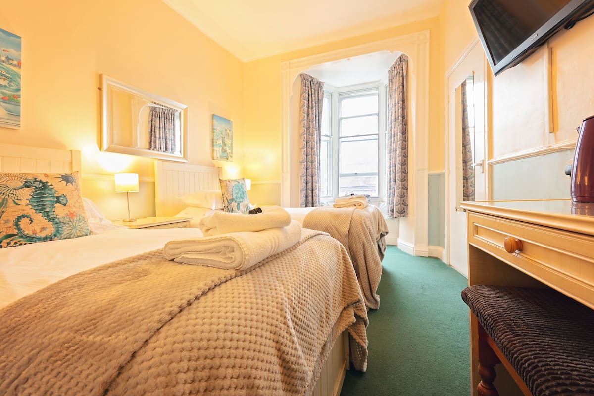 Een hotelkamer met twee bedden, een televisie en een raam met gordijnen.