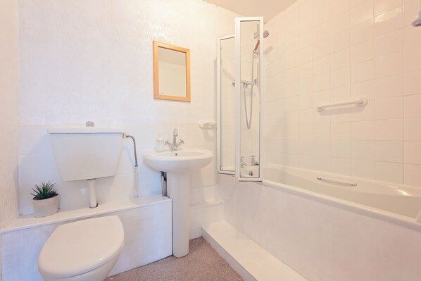 Une salle de bain avec des toilettes, un lavabo et une douche.