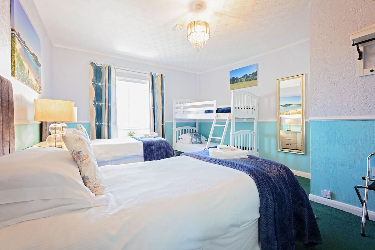 Een hotelkamer met een groot bed, een bureau, een stapelbed en een spiegel.