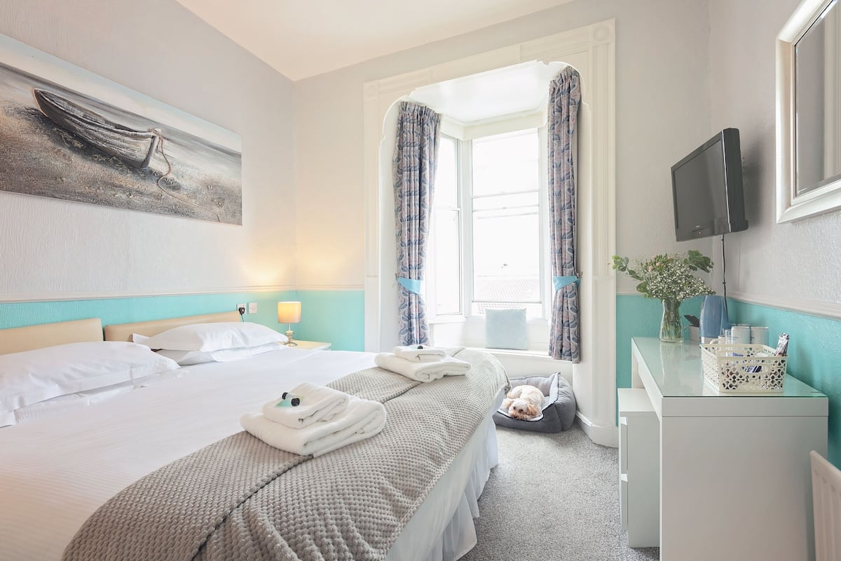 Hotelkamer met een bed, een bureau, een televisie en een raam met gordijnen.