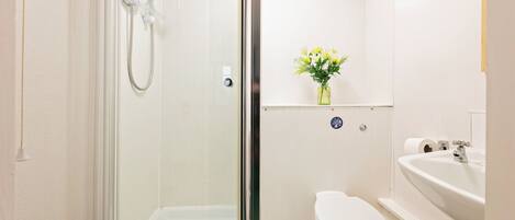 Une salle de bain avec une douche à parois de verre, des toilettes et un lavabo avec un miroir.