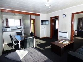A compact living space with a kitchenette, a dining area, a seating area with a coffee table, and a television.