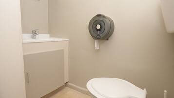 Een badkamer met toilet, wastafel en papieren handdoekdispenser.
