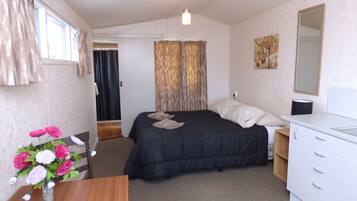 A bedroom with a bed, a dresser, a mirror, and a vase with flowers.