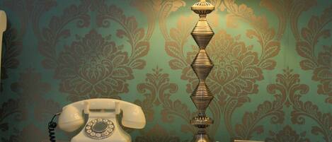 A white bedside table with a lamp and a rotary phone.