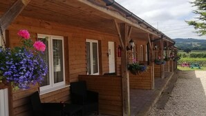 Une cabane en bois avec un porche, des sièges d’extérieur et des jardinières fleuries.