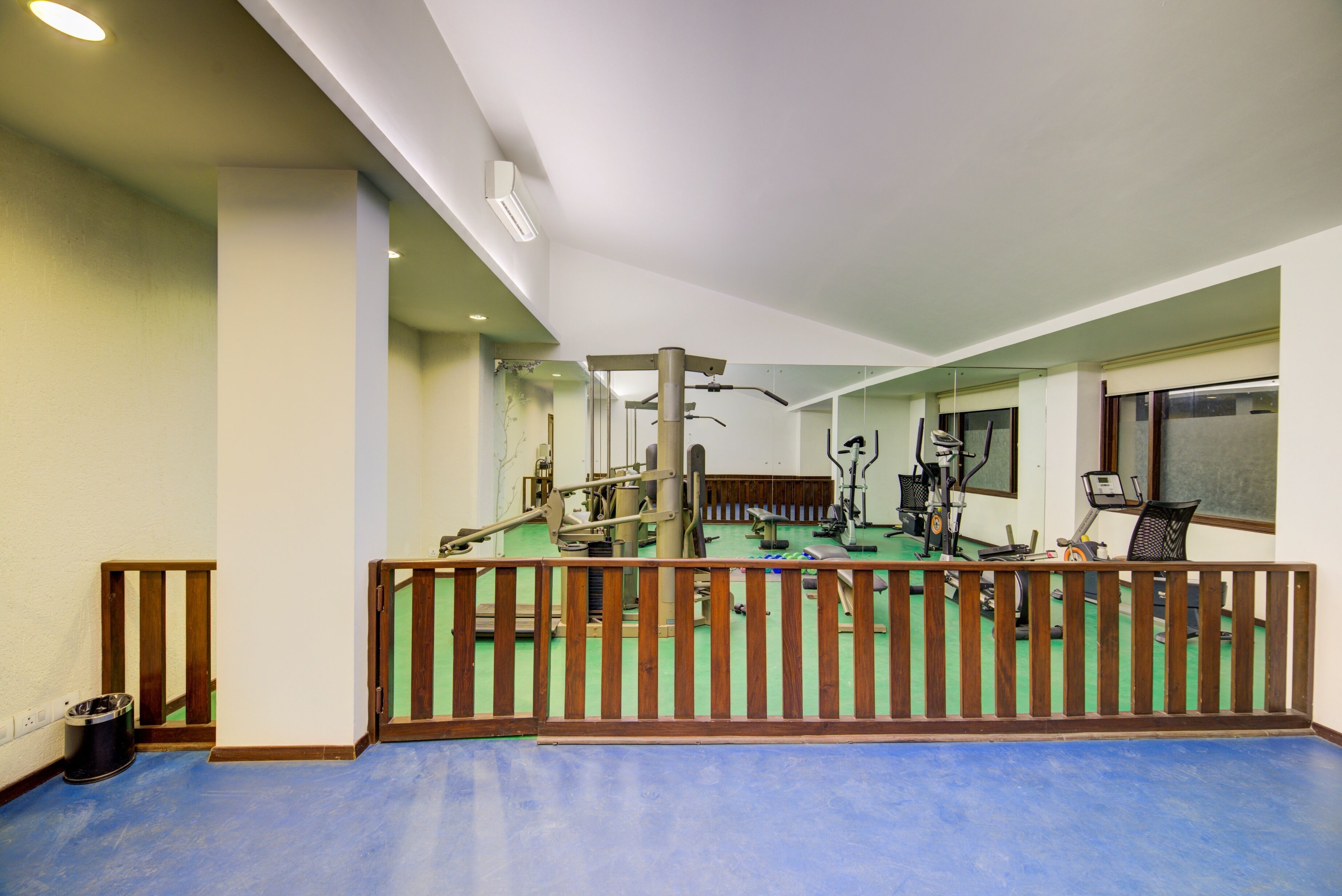 Una palestra con attrezzature per esercizi, una ringhiera in legno e un pavimento blu.