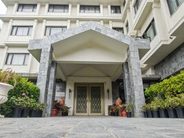 A building entrance with a stone facade, a gated door, and potted plants.
