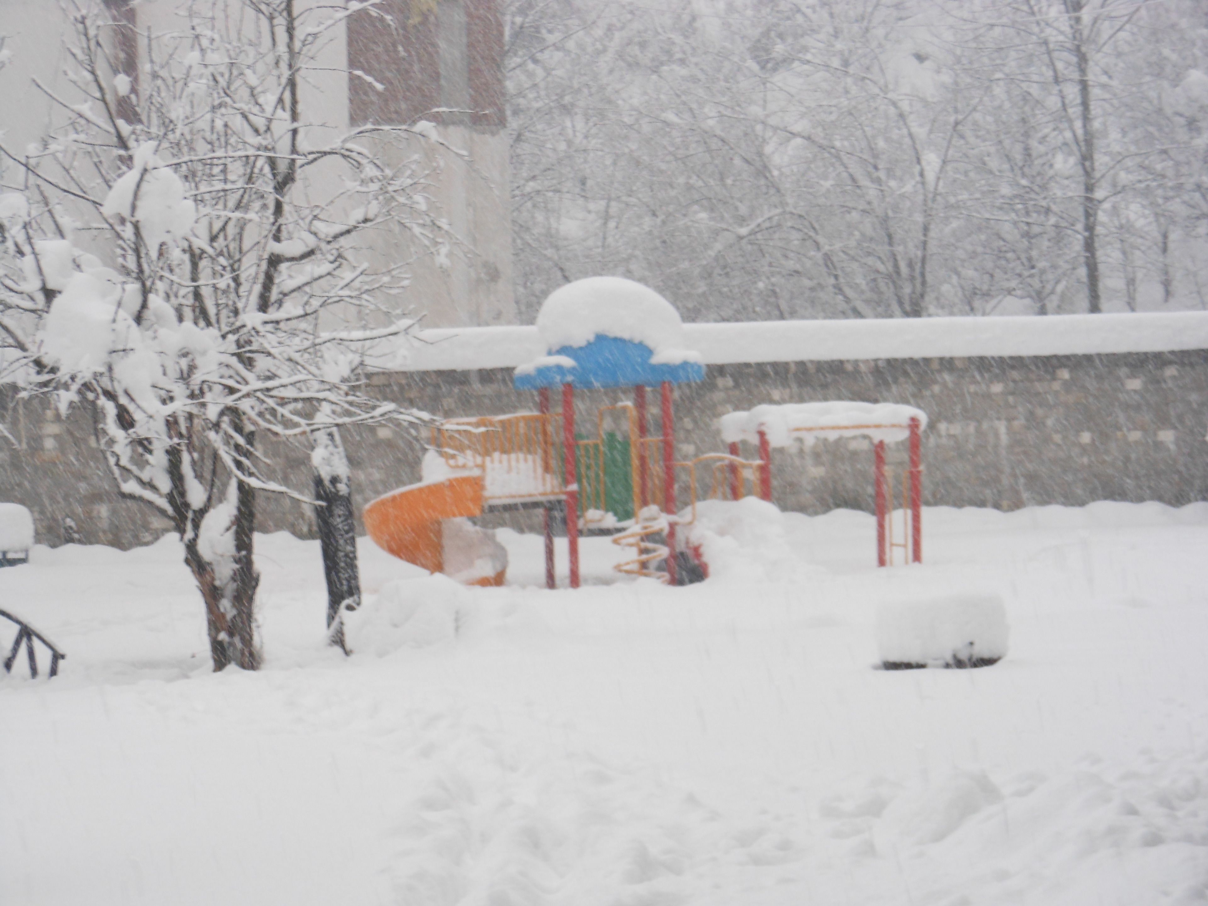 Ein mit Schnee bedeckter Spielplatz mit Rutsche und Klettergerüsten.