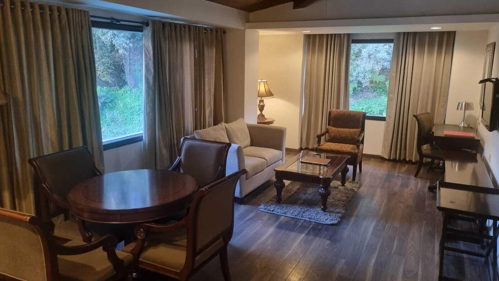 A living room with a round table, sofa, armchairs, and a coffee table.
