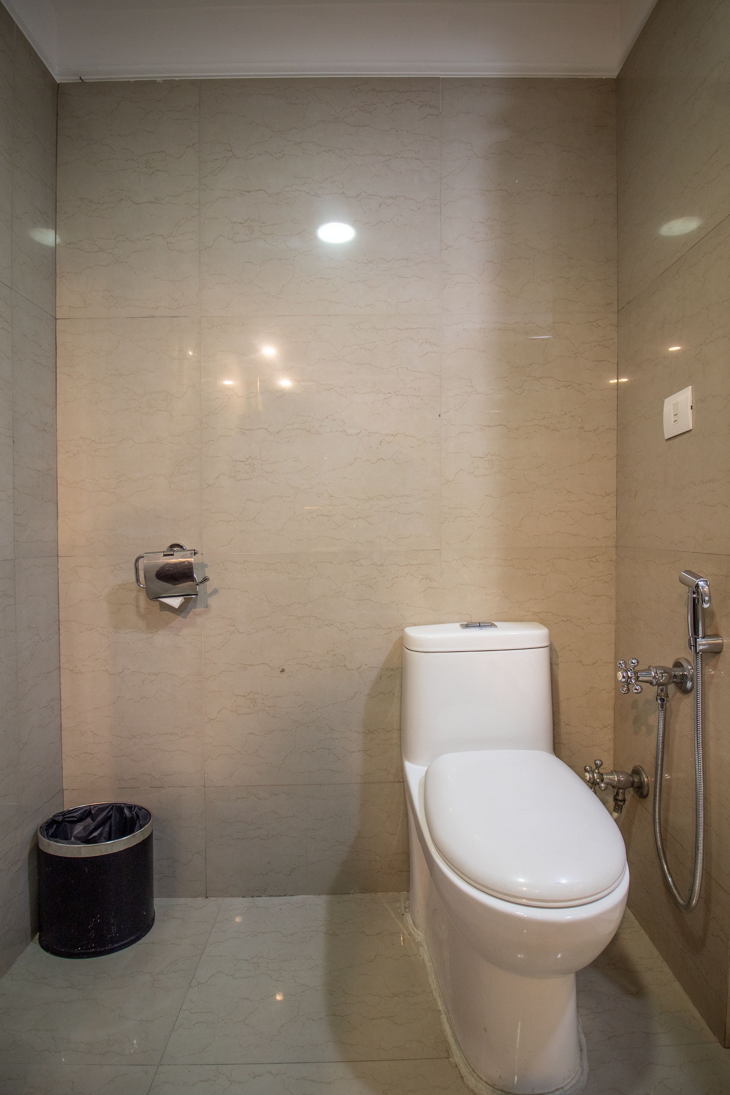 A modern bathroom with a toilet, bidet, and a trash bin.