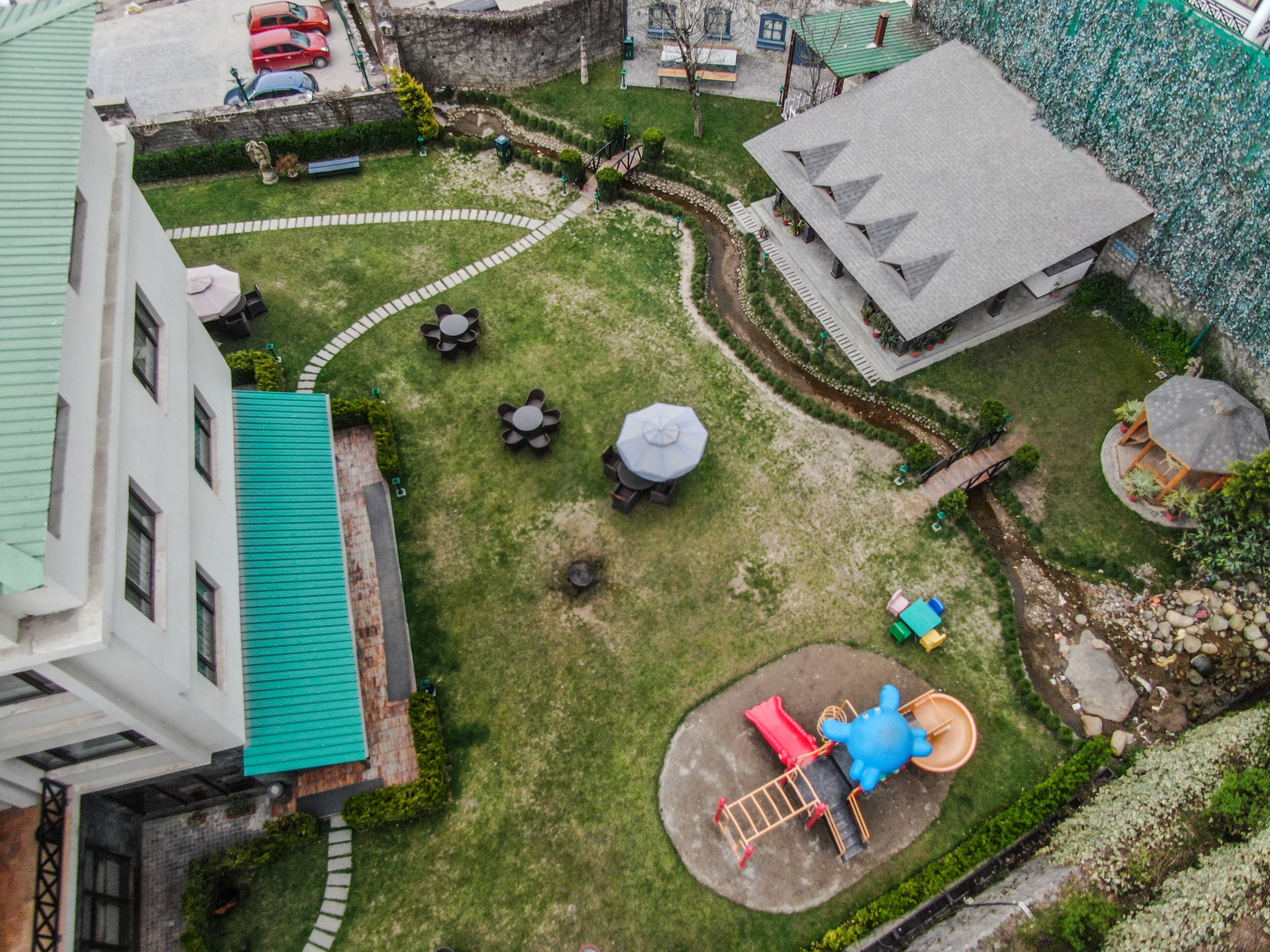 A courtyard with a playground, a covered seating area, and a building with a green roof.