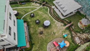 A courtyard with a playground, a covered seating area, and a building with a green roof.