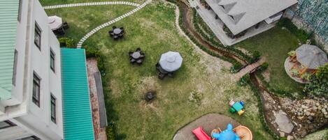 A courtyard with a playground, a covered seating area, and a building with a green roof.