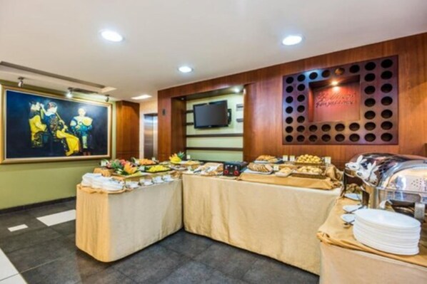 Mesa de buffet con diversos alimentos y un televisor montado en la pared.