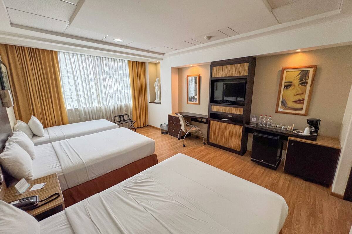 Een hotelkamer met twee bedden, een bureau, een televisie en een minibar.