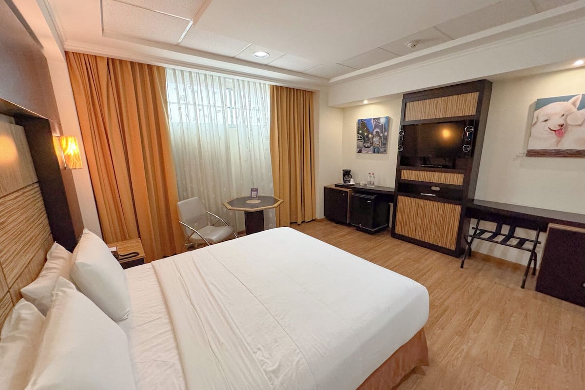 Een hotelkamer met een groot bed, een bureau, een stoel en een televisie.