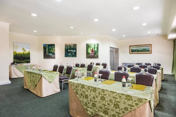 Un salón de conferencias con varias mesas, sillas y obras de arte en las paredes.
