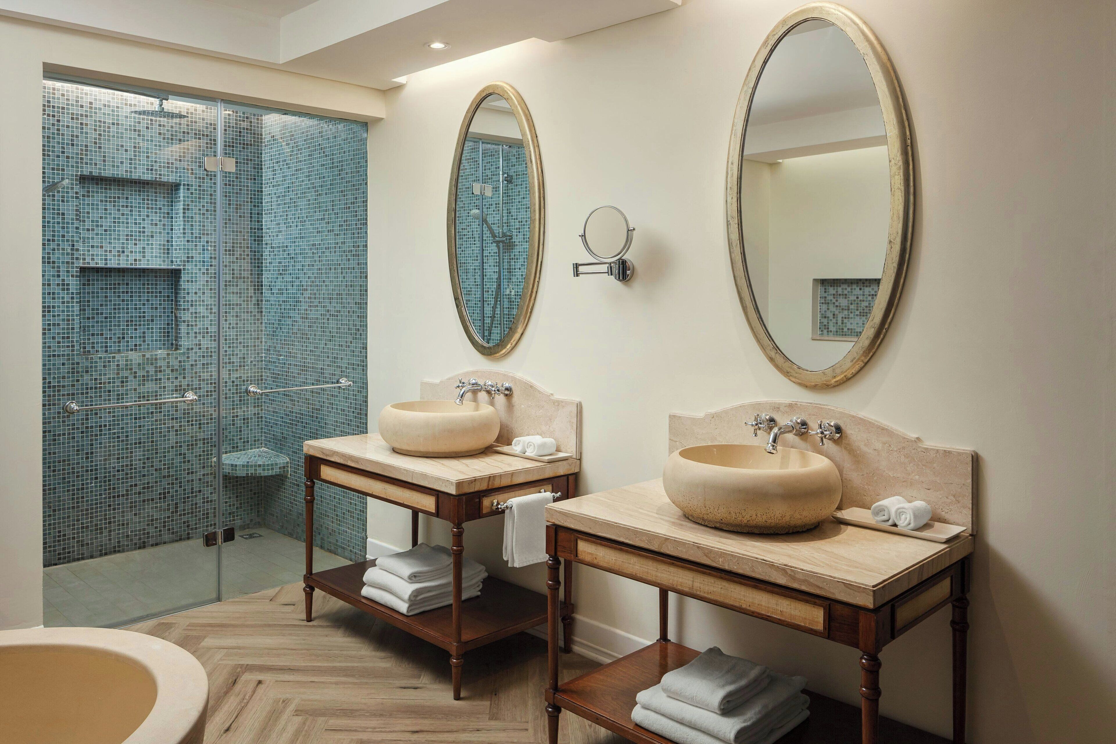 Une salle de bain avec deux lavabos, un grand miroir et un espace douche aux carreaux de mosaïque bleus.