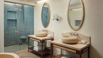 Une salle de bain avec deux lavabos, un grand miroir et un espace douche aux carreaux de mosaïque bleus.
