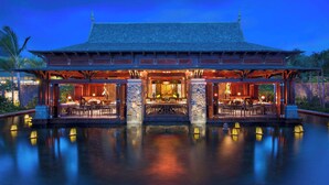 A traditional building with a tiled roof, a central open area with tables and chairs, and a surrounding water body. - The St. Regis Le Morne Resort, Mauritius (Le Morne)