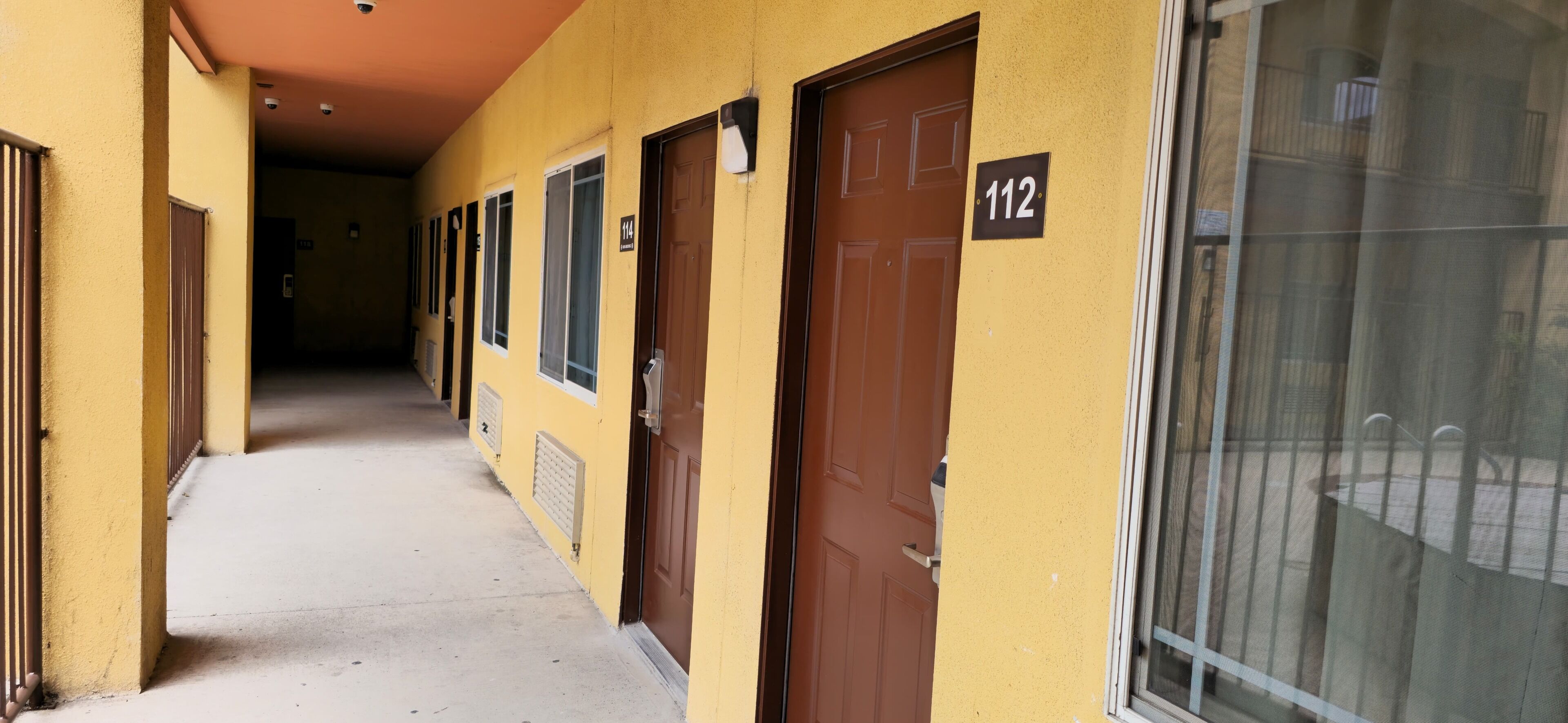 Un pasillo con puertas numeradas 114 y 112, que conduce a habitaciones individuales.