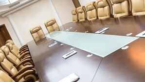 A conference room with a glass table, leather chairs, and a whiteboard. - Texas Inn and Suites RGV (Edinburg)
