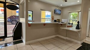 A reception area with a counter, a ceiling fan, a television, and a Buddha statue. - Texas Inn and Suites RGV (Edinburg)
