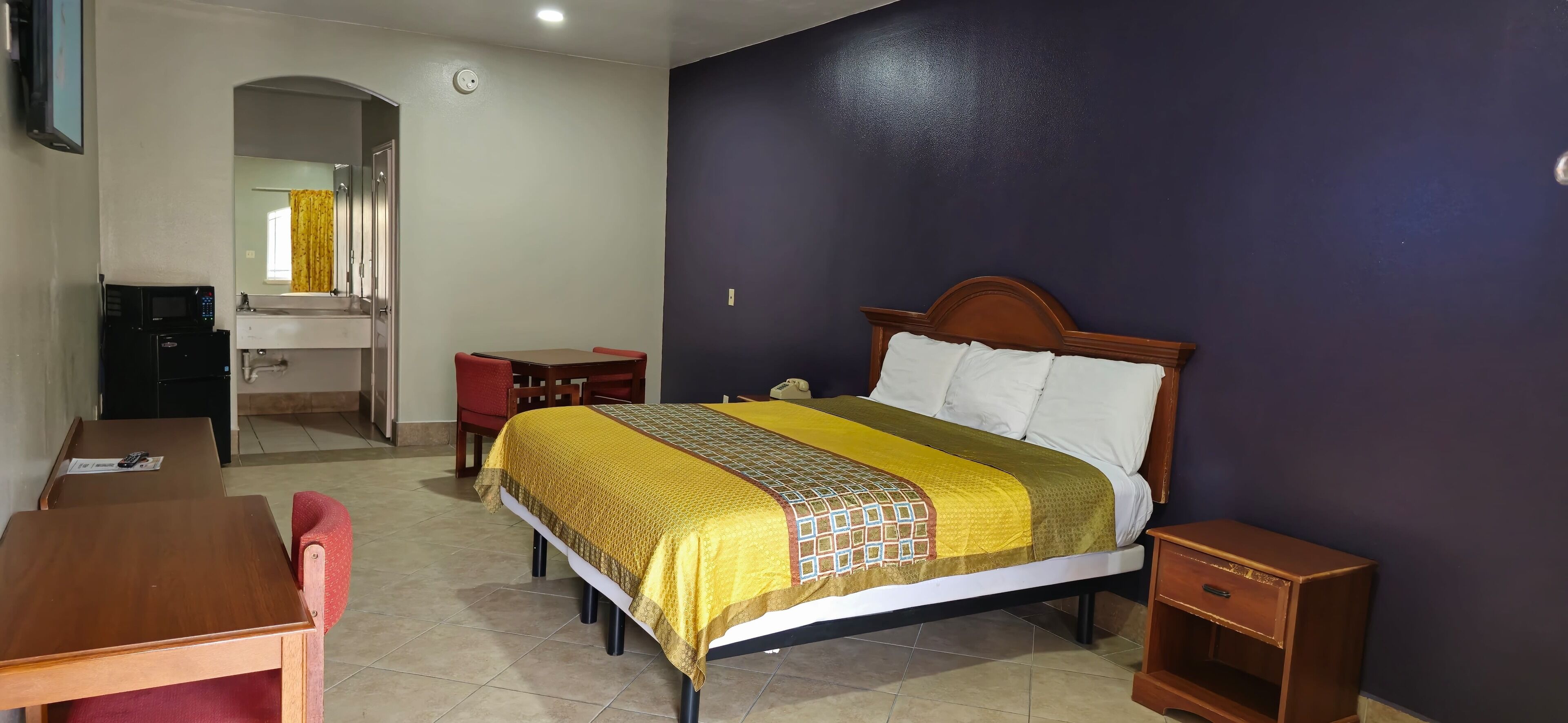 Una camera d'albergo con un letto, una scrivania, una sedia, un tavolino e un armadio.