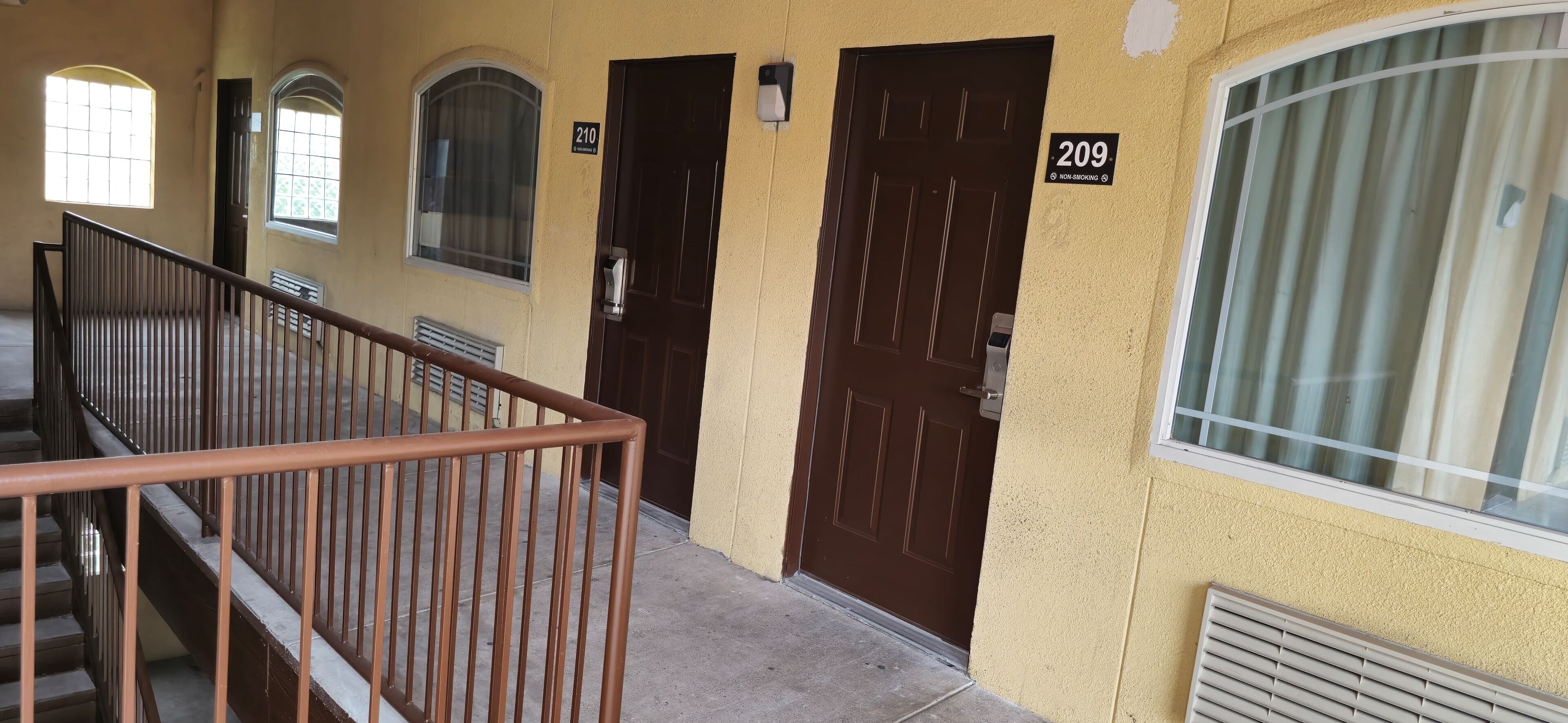 A building with numbered doors, a staircase, and a window with blinds.