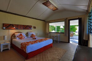 A bedroom with a bed, bedside table, and a view of the outdoors. - Sandy Beach Resort (Faleloa)