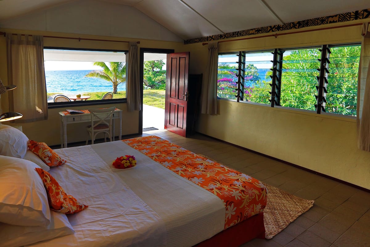 A hotel room with a bed, a desk, and a view of the ocean.