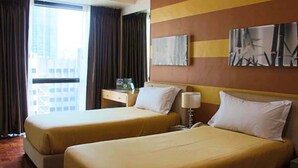 A hotel room with two beds, a nightstand, a lamp, and a window with curtains. - Asian Mansion Il (Makati)