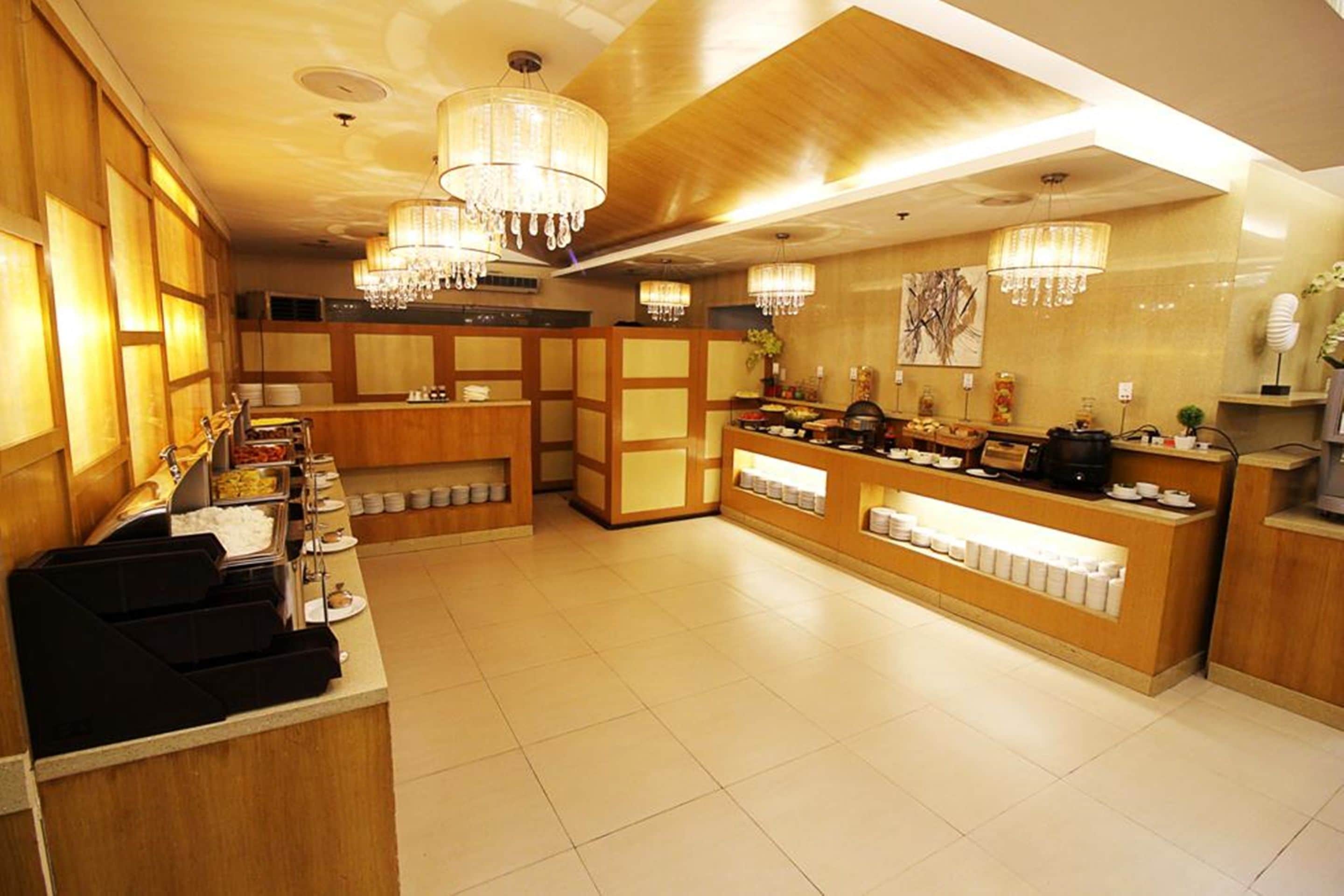 A hotel reception area with wooden paneling, a buffet counter, and chandeliers.