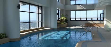 An indoor swimming pool with large windows offering views of the cityscape.