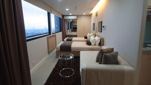 Een moderne hotelkamer met een groot raam, twee bedden, een klein rond tafeltje en een bank.